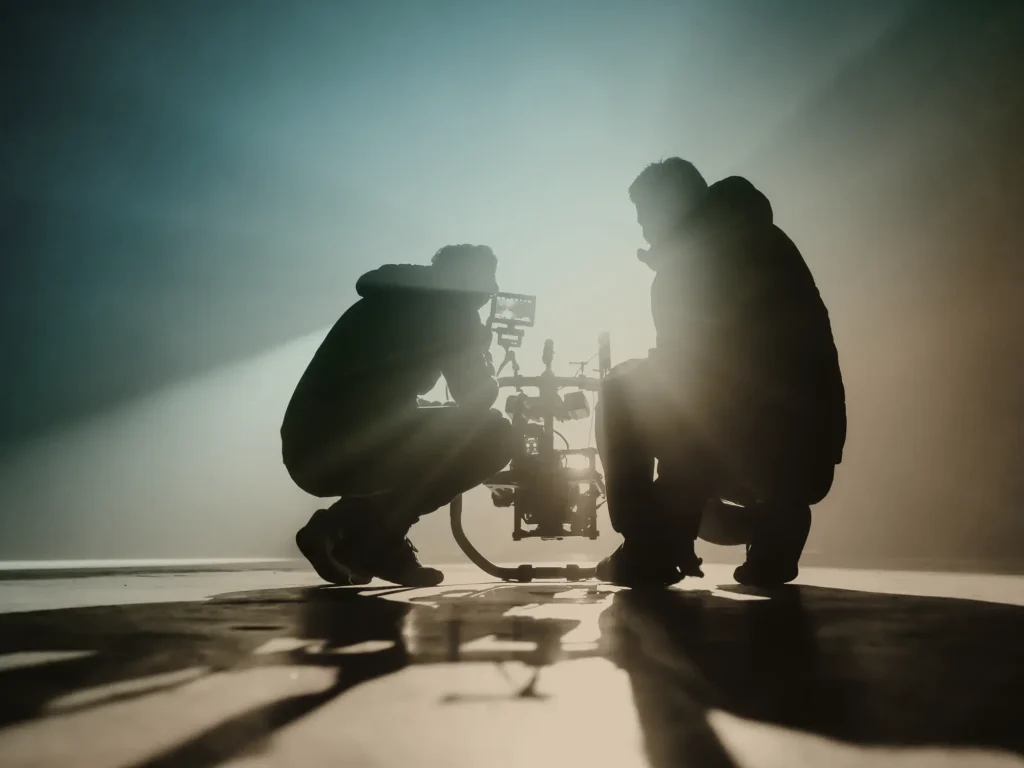 Silhouette of camera people on a production set, with dramatic lens flare